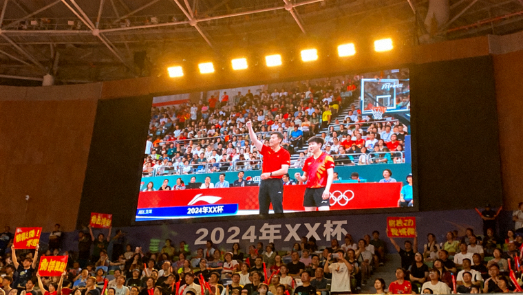 体育赛事直播现场画面，赛场大屏幕与观众看台